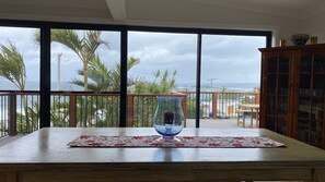 A balcony with a view of palm trees and the ocean, a glass vase on a table, and a wooden cabinet. - Manyana Views with expansive views (Manyana)