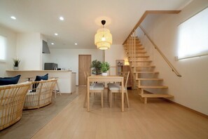 Eine moderne Küche mit Essbereich, einer Treppe und einer hängenden Leuchte.