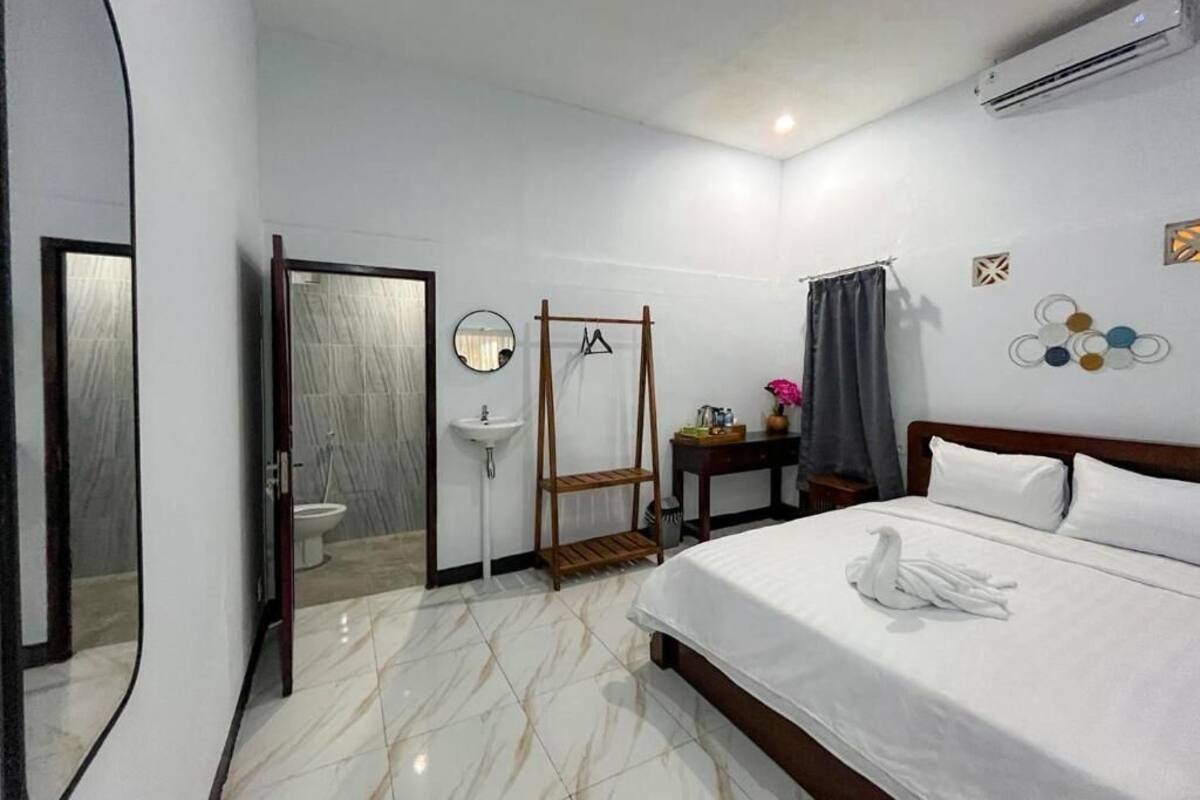 Una habitación de hotel con cama, espejo, lavabo, tocador y ventana con cortinas.