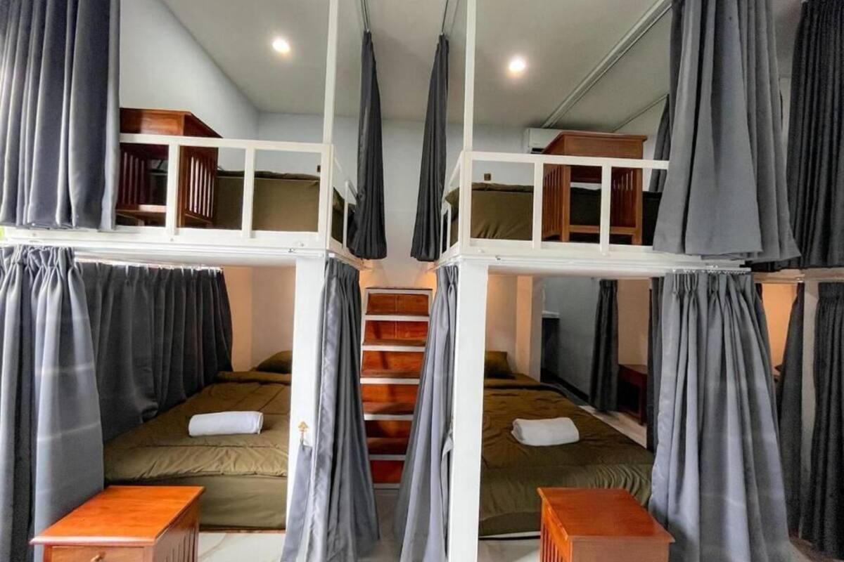 Habitación tipo dormitorio con literas, un escritorio de madera y una escalera.