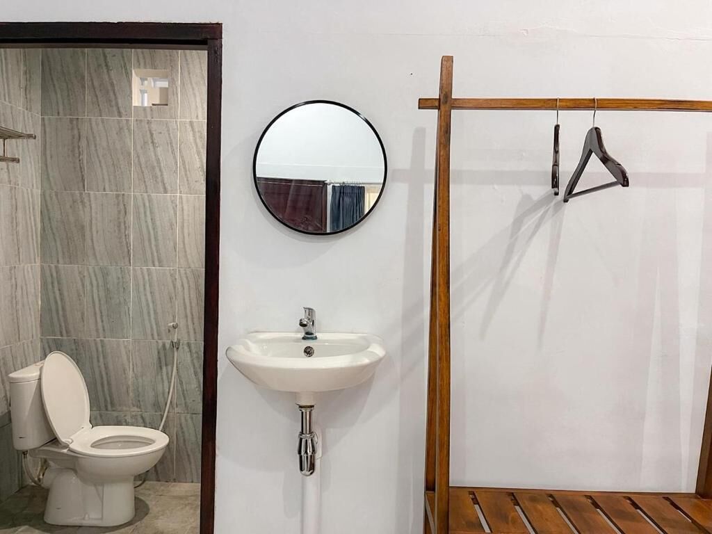 A bathroom with a toilet, sink, and mirror.