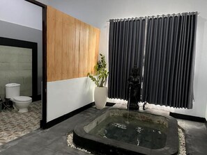 Une salle de bain avec une baignoire, des toilettes, une plante en pot et une fenêtre avec des rideaux.