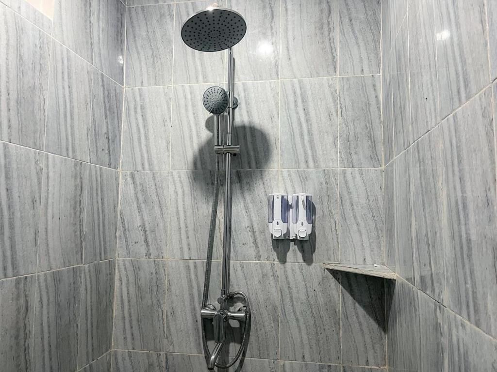 A shower with a handheld showerhead and a wall-mounted control panel.