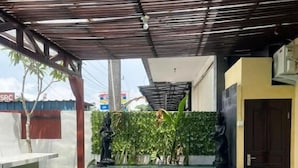 Una piscina con fondo de cristal, rodeada por una zona techada con techo metálico y una pared verde con plantas.