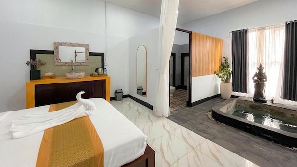 Habitación de hotel con cama, tocador con espejo, baño pequeño y vistas a una zona de piscina.