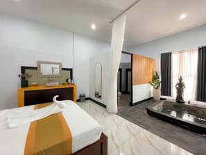 Habitación de hotel con cama, tocador con espejo, baño pequeño y vistas a una zona de piscina.