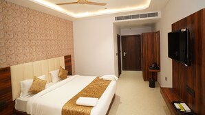A hotel room with a bed, a ceiling fan, a TV, and a wooden wardrobe. - Avdhesh Palace (Tarabganj)