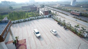 A hotel parking lot with two white cars parked. - Avdhesh Palace (Tarabganj)