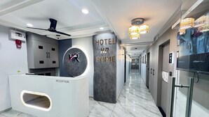 En hotellobby med modern design, inklusive en receptionsdisk, en digital skärm och en hall som leder till gästrummen.