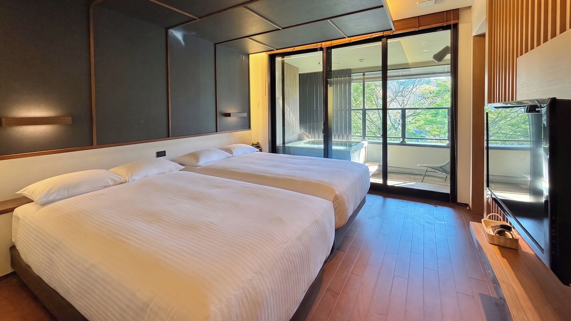 A hotel room with two beds, a large window, and a television.