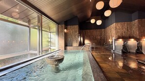 Un área de spa con un ventanal grande, una bañera de hidromasaje y una pared de madera.
