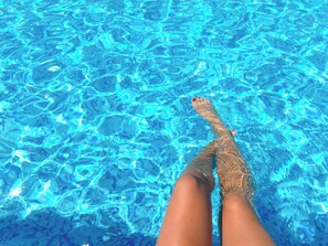 A view of a swimming pool with clear blue water and a person's legs submerged in it. - 4-Bedroom Villa, Pool, Game Room, Near The Beach & Hard Rock Hotel (Pembroke Pines)