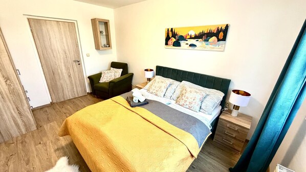Ein Schlafzimmer mit einem Bett, einem Sessel, einem Nachttisch, einer Lampe und einem Bild an der Wand.