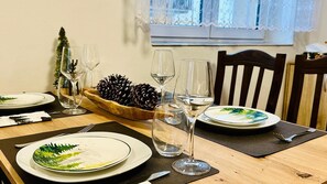 A dining table set with plates, glasses, and a pine cone centerpiece.
