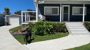 Une maison d’habitation avec un porche à l’avant, un petit jardin et un chien.