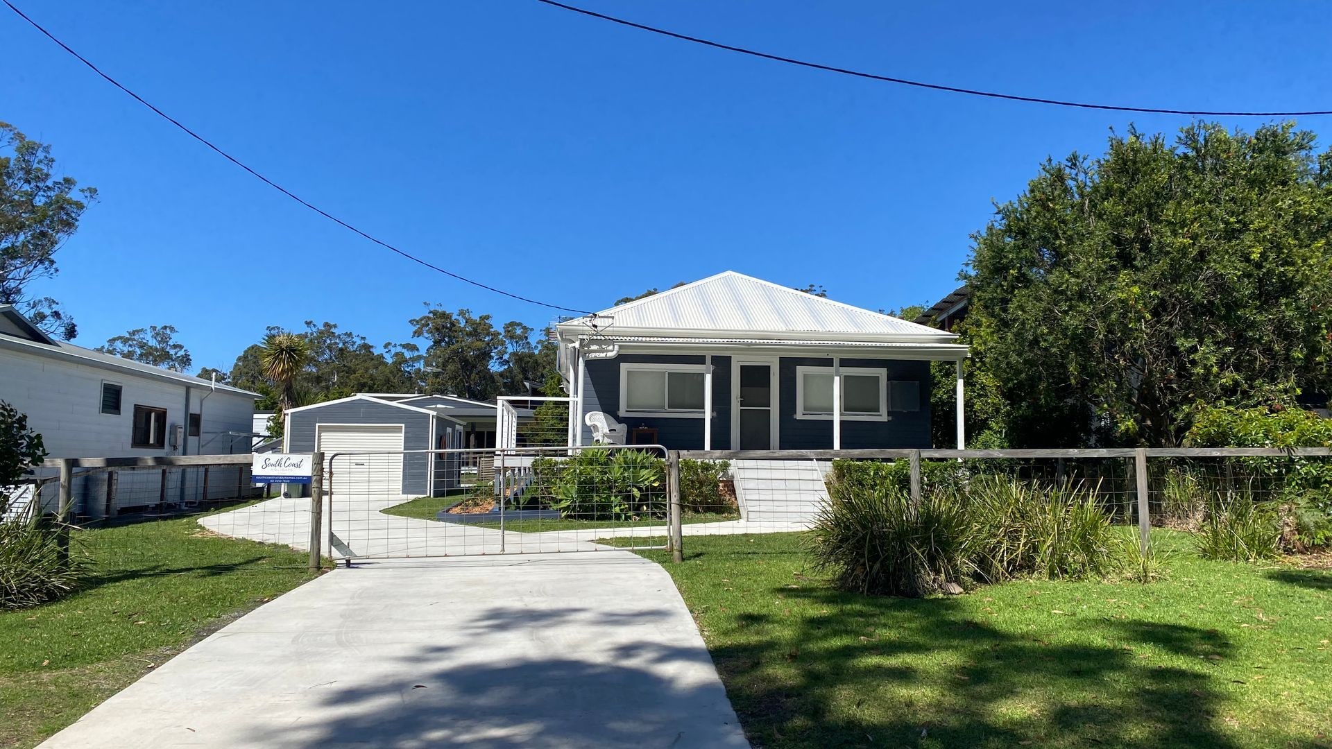 A residential area with a house featuring a garage, a covered porch, and a fenced yard.