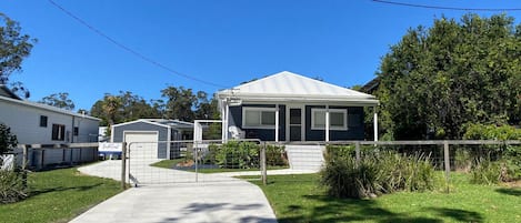 A residential area with a house featuring a garage, a covered porch, and a fenced yard.