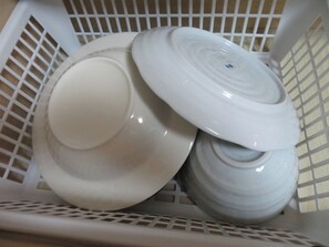 Ein weißer Plastikkorb mit mehreren weißen Keramiktellern und Schüsseln.