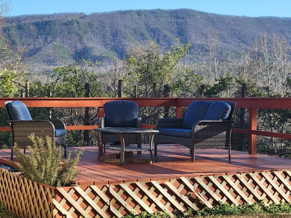 Una terraza con mobiliario de mimbre y vistas a una montaña boscosa.