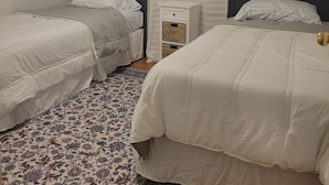 A bedroom with two single beds, a ceiling fan, a nightstand, a patterned rug, and two framed floral pictures on the wall. - Mountain view retreat, 3 bedroom overlooking the Foothills. (Maryville)