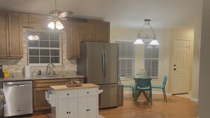 A modern kitchen with wooden cabinets, a stainless steel refrigerator, and a dining area with a table and chairs. - Mountain view retreat, 3 bedroom overlooking the Foothills. (Maryville)