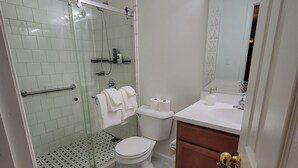 A bathroom with a glass-enclosed shower, a toilet, a sink, and a mirror. - Mountain view retreat, 3 bedroom overlooking the Foothills. (Maryville)