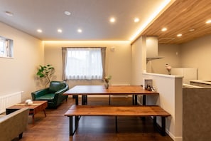 A modern living room with a wooden dining table, green sofa, and a small coffee table. - FLEX CELLA NORTH17 B Maximum 10 3LDK / Higashi Ward, Sapporo Hokkaidō (Higashi Ward, Sapporo)