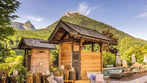 A wooden cabin with a pool area, surrounded by lush greenery and mountains. - Gams - apartment - balcony with mountain view, fireplace - 65sqm, non-smoking (Ramsau bei Berchtesgaden)