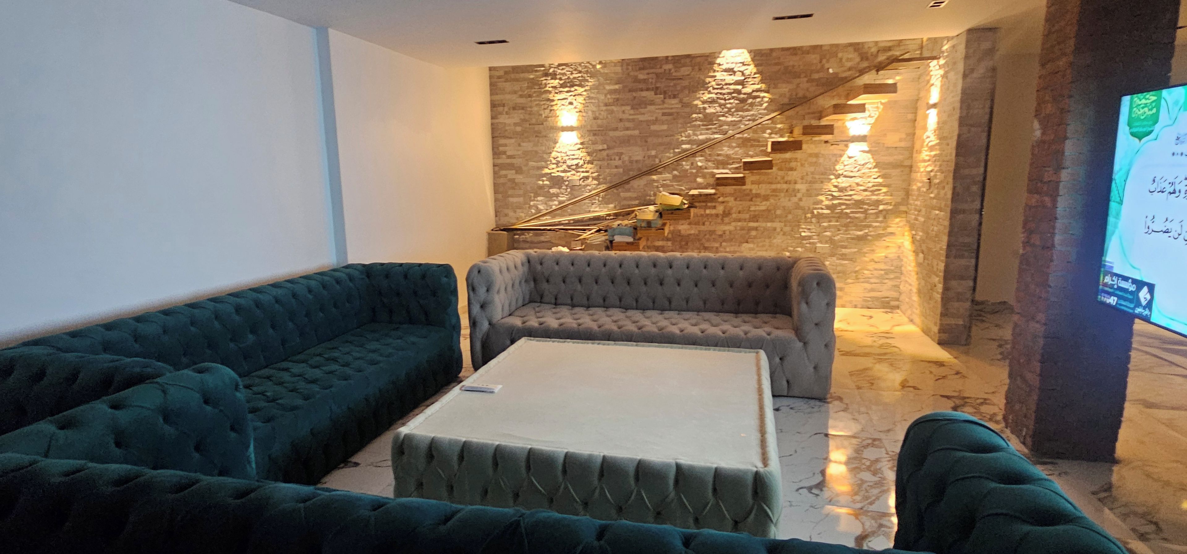 A modern living room with a stone wall, a staircase, and a flat-screen TV.