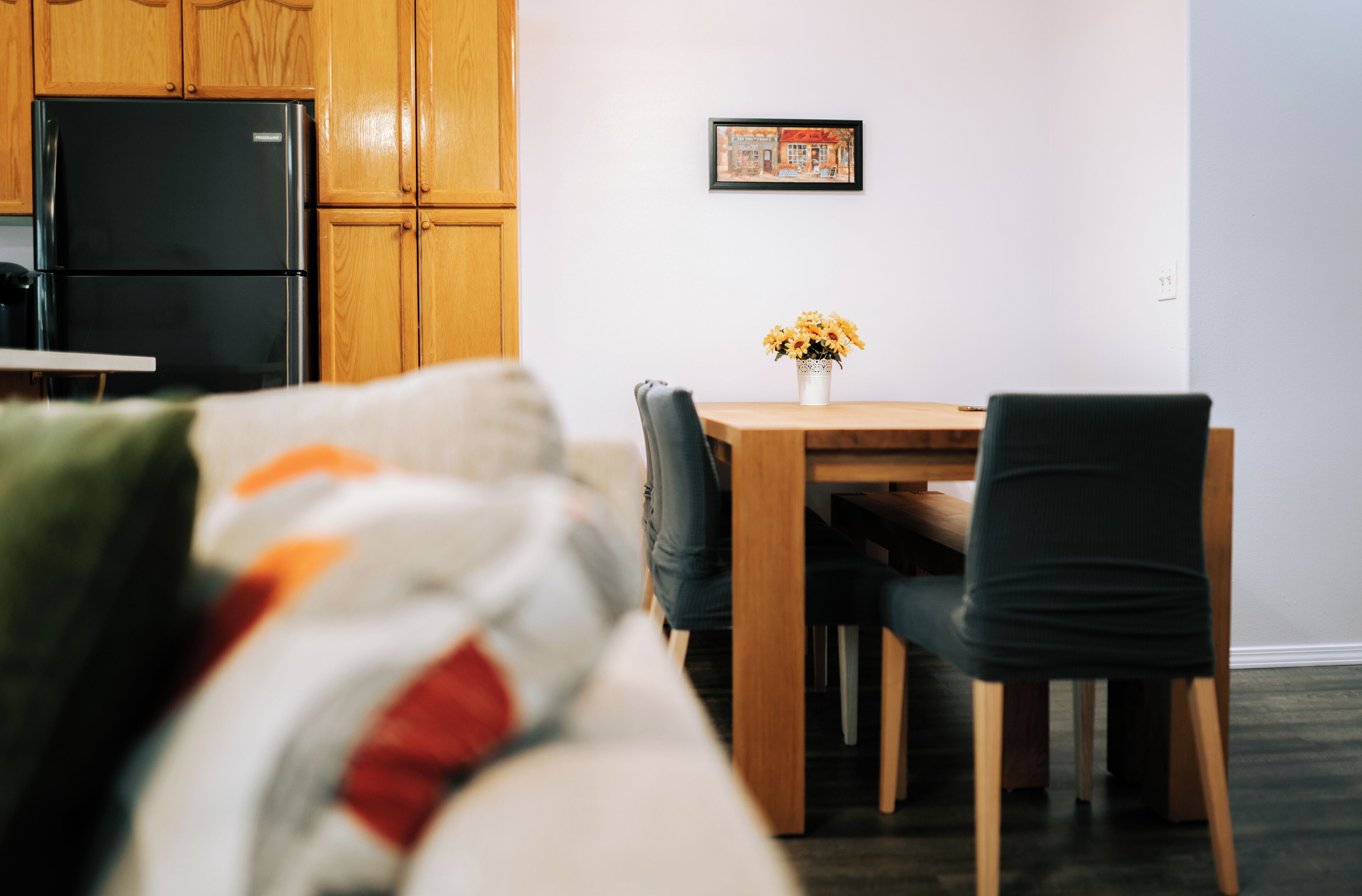 A modern kitchen with wooden cabinets and a black refrigerator.