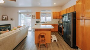 A modern kitchen with wooden cabinets, a black refrigerator, and a central island with a stool. - Jan-Mar 30% Monthly Discount Modern 3B/2.5B Entire House Nike (Beaverton)