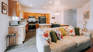 A modern kitchen with wooden cabinets, stainless steel appliances, and a dining area with a table and chairs. - Jan-Mar 30% Monthly Discount Modern 3B/2.5B Entire House Nike (Beaverton)