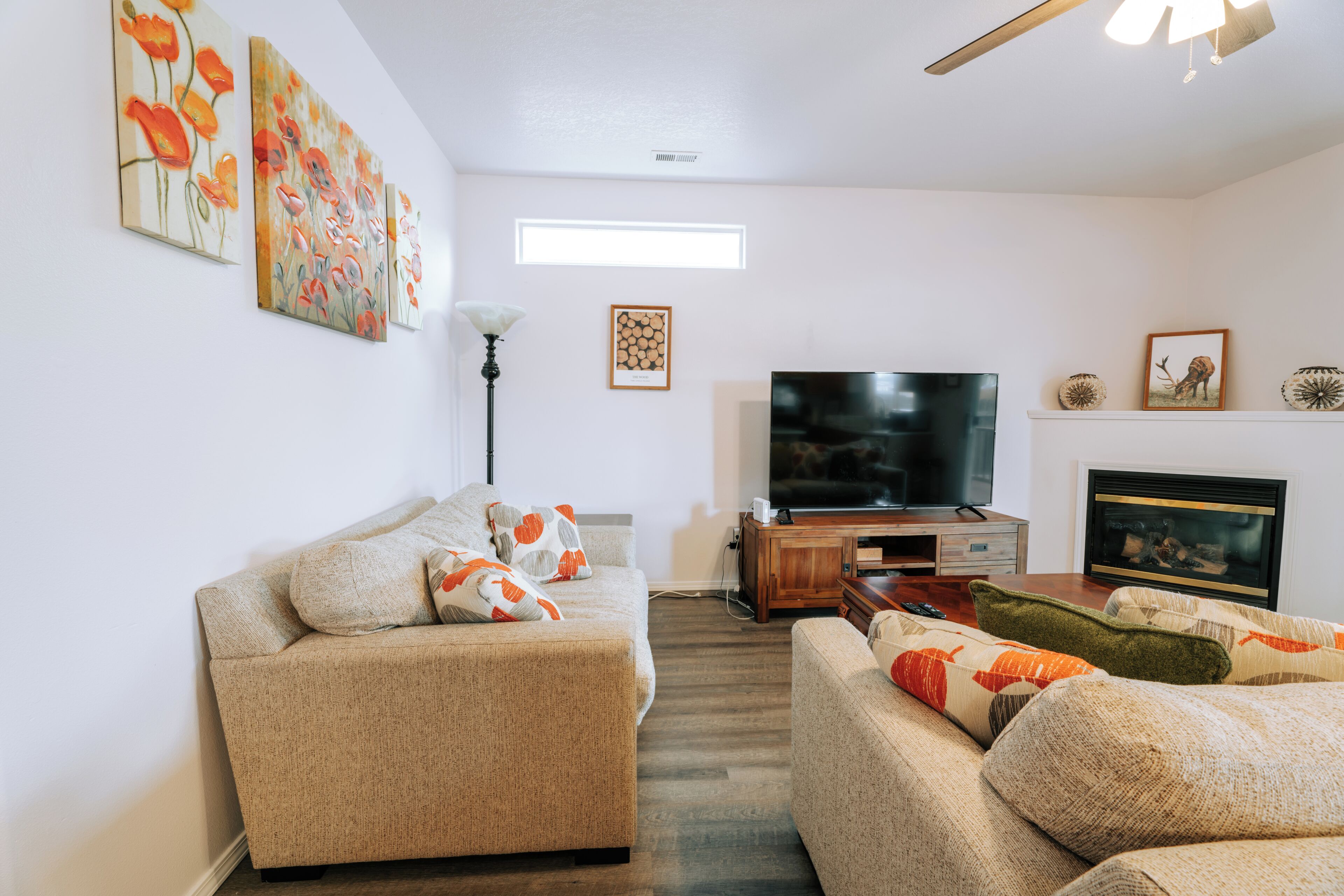 A living room with a sofa, a television, a fireplace, and wall art.