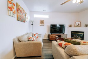 Ein Wohnzimmer mit einer Couch, einem Fernseher, einem Kamin und Wandbildern.