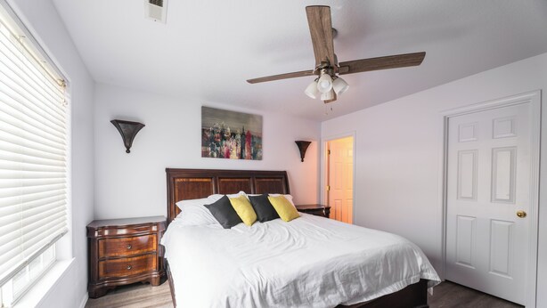 A bedroom with a bed, a nightstand, a ceiling fan, a door, and a window with blinds. - Jan-Mar 30% Monthly Discount Modern 3B/2.5B Entire House Nike (Beaverton)