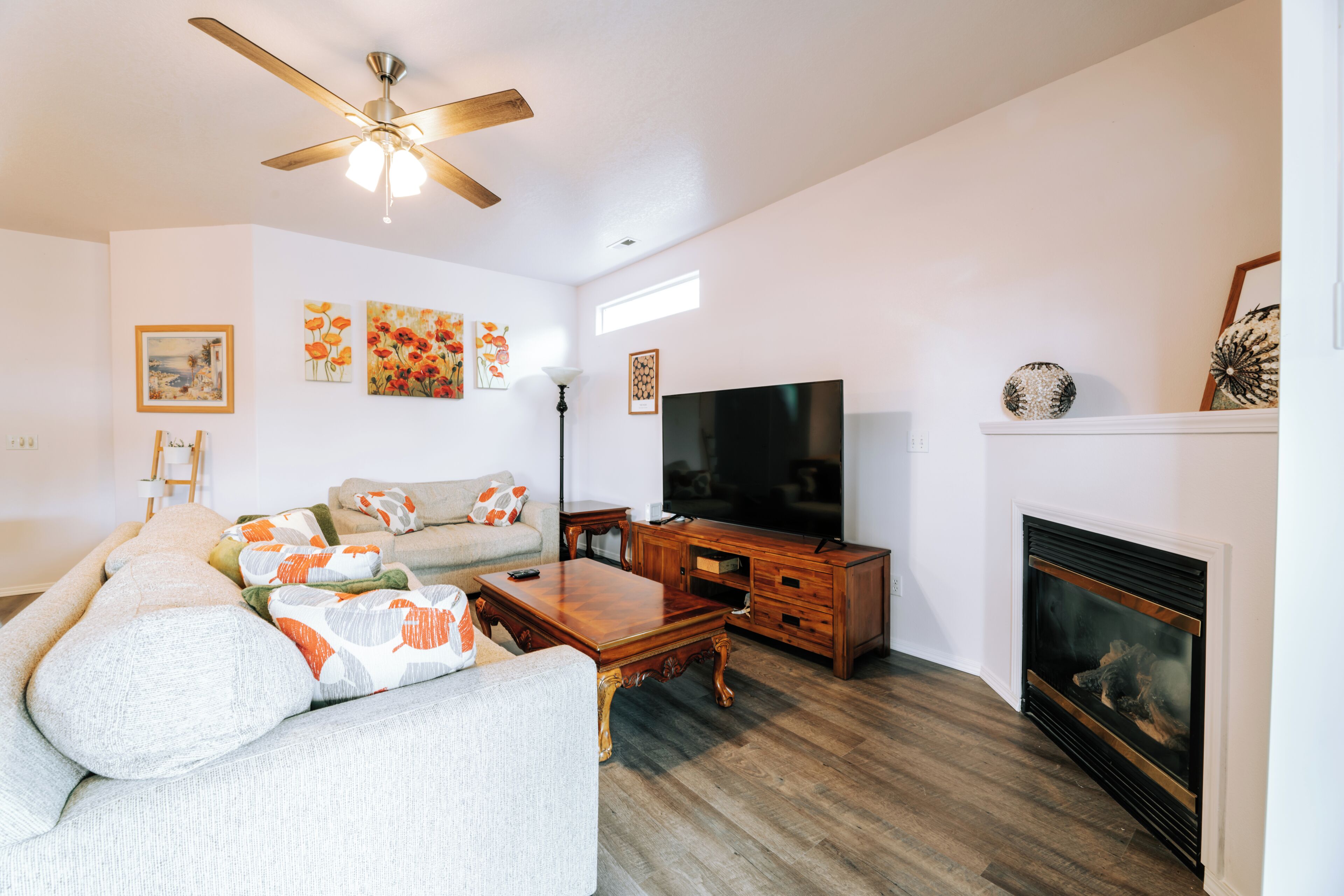 A living room with a sofa, coffee table, TV, fireplace, and artwork on the walls.