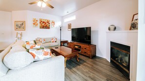 A living room with a sofa, coffee table, TV, fireplace, and artwork on the walls. - Jan-Mar 30% Monthly Discount Modern 3B/2.5B Entire House Nike (Beaverton)