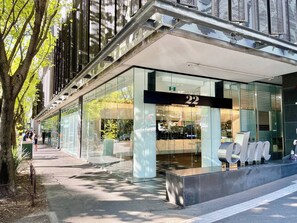 A modern building with a glass facade, a prominent entrance number 22, and a covered walkway. - The Elm - 2 bedrooms, FREE Parking, Pool & Gym (Southbank)