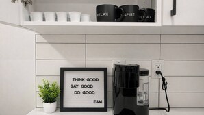 Une cuisine équipée d’une machine à café, d’une plante en pot et d’une affiche aux messages inspirants.