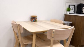 Une table à manger en bois, avec quatre chaises, une petite plante en pot et une citation encadrée accrochée au mur.