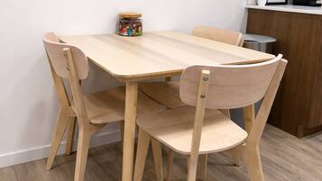 Une table à manger en bois, avec quatre chaises, une petite plante en pot et une citation encadrée accrochée au mur.