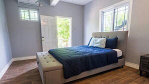 Un dormitorio con cama, un banco, una ventana y una puerta.