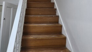 Una escalera de madera con paredes blancas y tres cuadros enmarcados.
