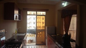 Una cocina con estufa a gas, lavamanos y armarios. Se ve una ventana con vistas a edificios.