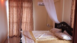 Una cama individual con cabecera de madera, dosel blanco y ropa de cama estampada.