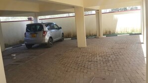 Un área de estacionamiento techada con piso pavimentado y un automóvil dentro.