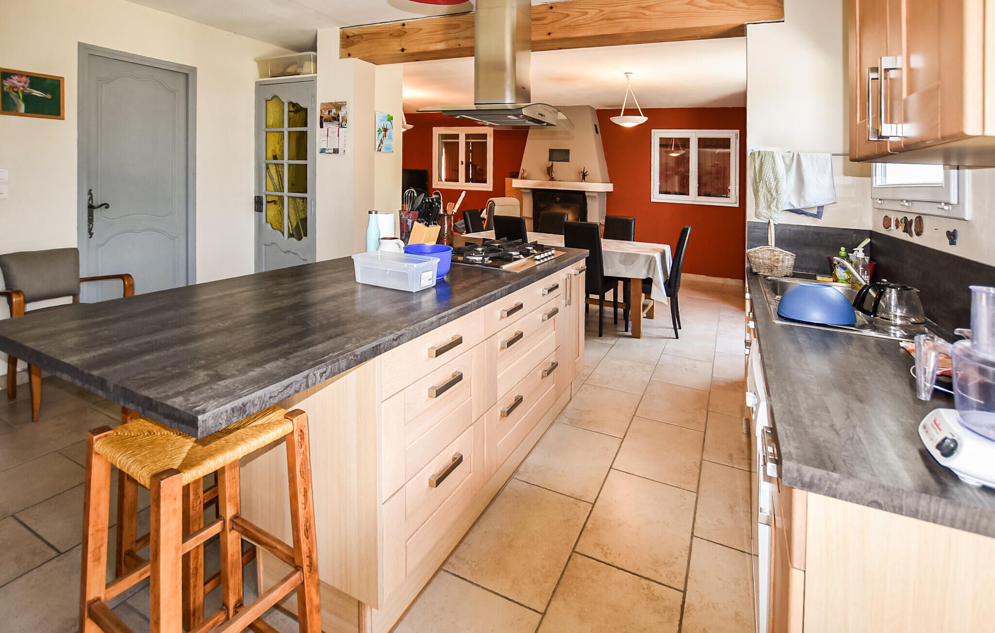 A spacious kitchen with a large island, wooden cabinets, and a dining area with a table and chairs.