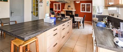 A spacious kitchen with a large island, wooden cabinets, and a dining area with a table and chairs.