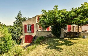 A rustic house with a stone wall, a red door, and a large tree providing shade. - Nice home in Taulignan (Taulignan)