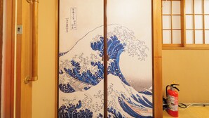 Puerta corrediza japonesa tradicional con pintura de olas, marco de madera y un extintor en la habitación.